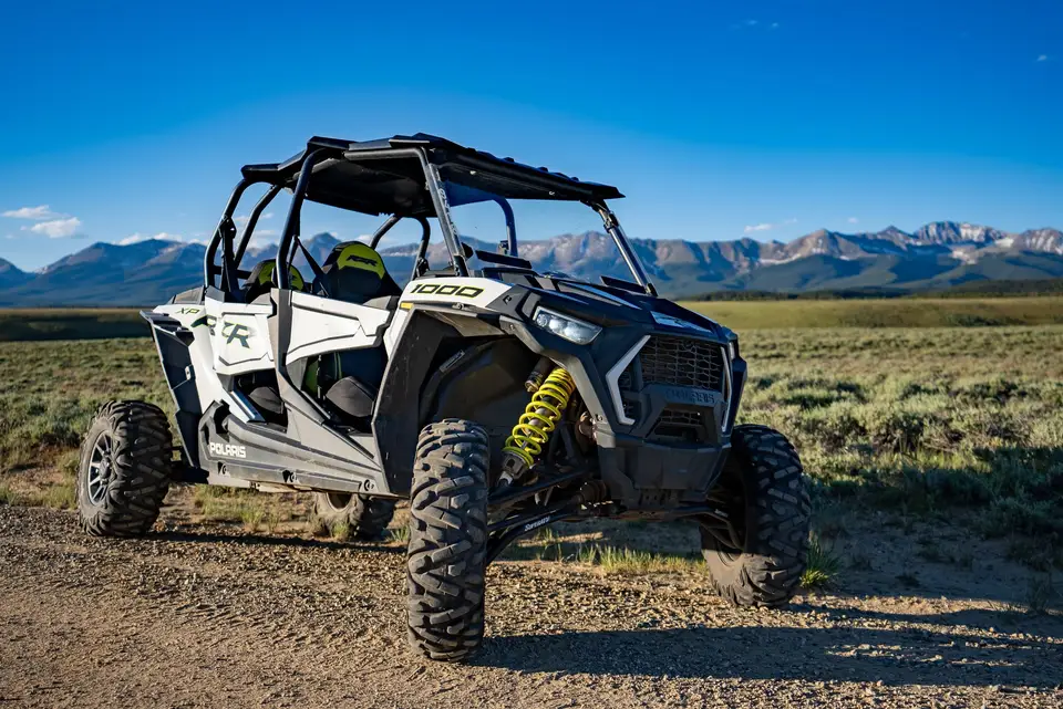A RZR in the evening light with the mountains on the horizon