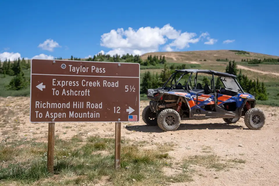 A Polaris RZR parked beside the Forest Service sign at Taylor Pass